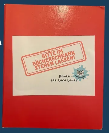 Roter Ordner mit dem Aufkleber Bitte im Bücherschrank stehen lassen